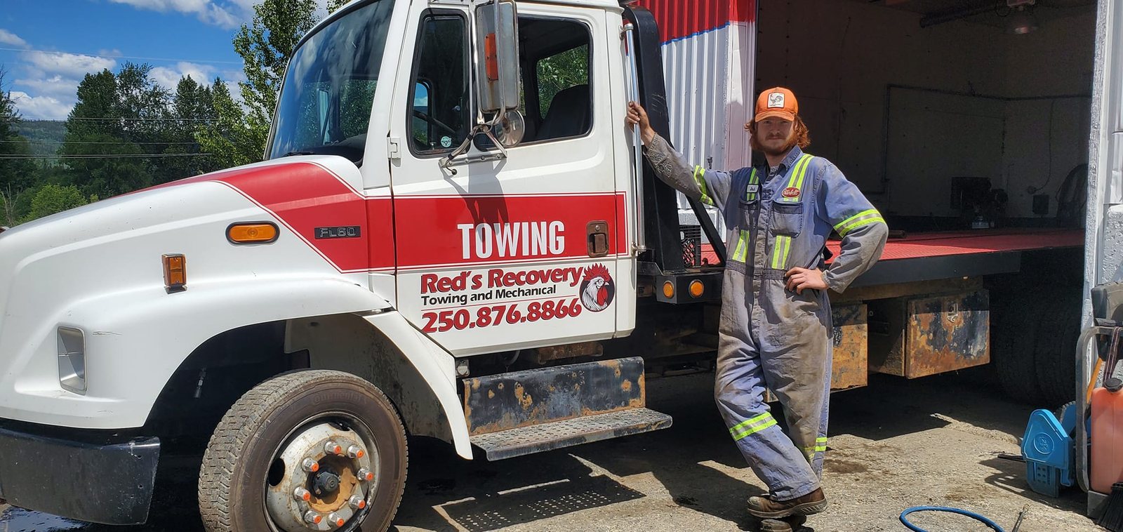 Red's Recovery mechanic standing beside the flatbed tow truck